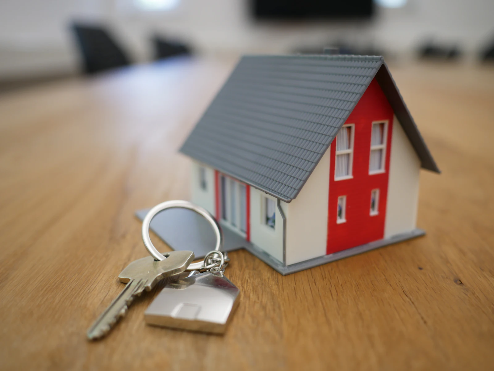 A small white model house with a red roof on a wooden table