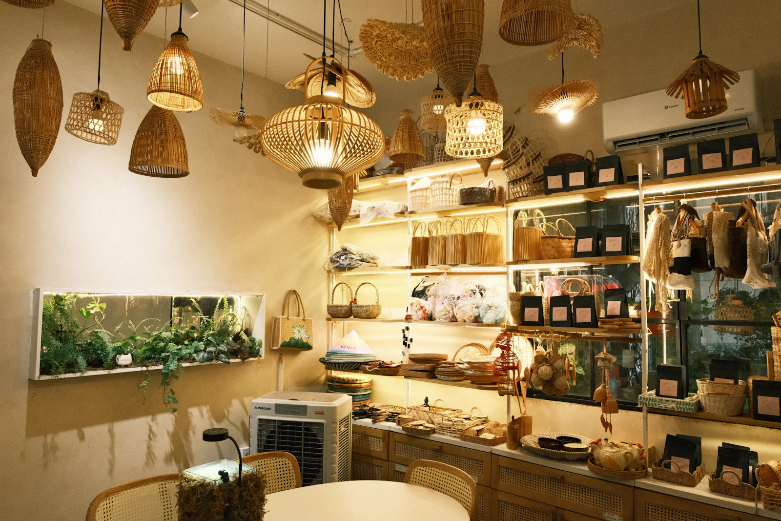 A warm shop interior with woven lamps over shelves of goods